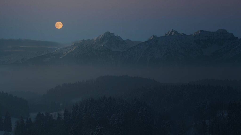 silhouette of mountains covered with light mist under the full moon